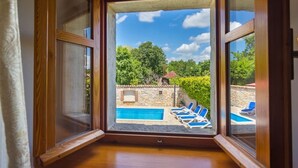 Una habitación con un ventanal grande con vistas a una piscina y zona de estar al aire libre.