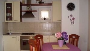 Uma cozinha com mesa, cadeiras e um relógio na parede.