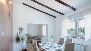 Ein Essbereich mit Tisch für vier Personen, einer Zimmerpflanze und Blick ins Freie durch ein Fenster.