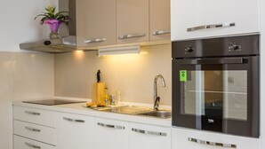 Une cuisine moderne avec des meubles blancs, des appareils en acier inoxydable, un évier et une petite plante en pot.