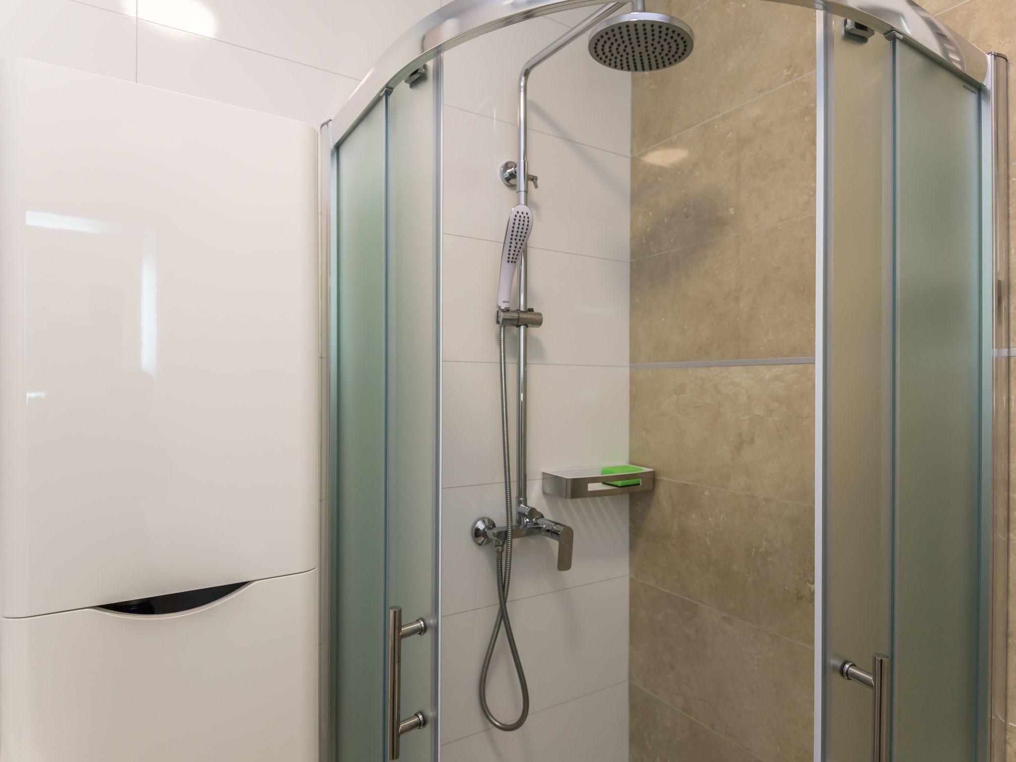 Ducha con mampara de vidrio, cabezal de ducha de mano y grifo de mano.