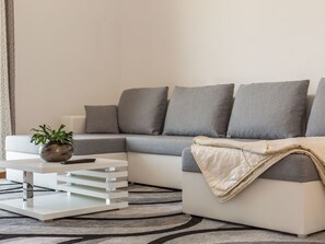 A modern living room with a grey sectional sofa, a white coffee table, and a patterned rug. - Große Wohnung in Omiš mit Möbliertem Balkon by Interhome (Omiš)