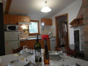 Ein Essbereich mit Tisch für vier Personen, einer Weinflasche und einem Kamin.
