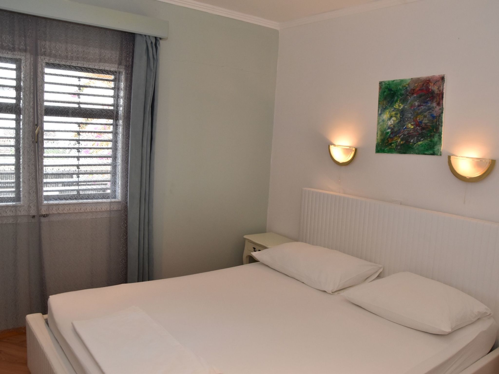 A bedroom with a bed, a nightstand, a radiator, and two wall-mounted lights.