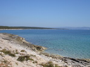 Paisagem costeira com terreno rochoso e mar azul cristalino.