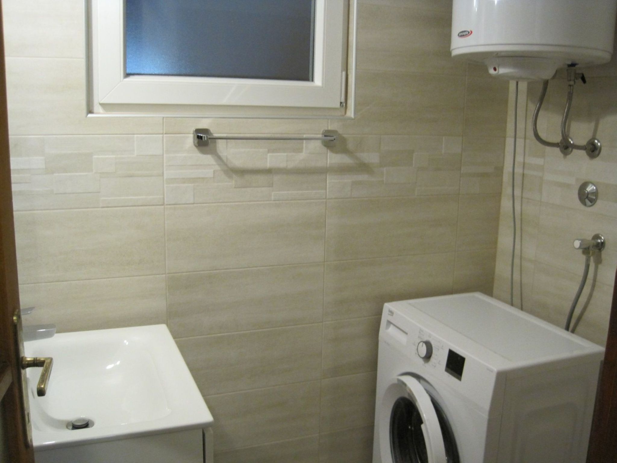 A small bathroom with a sink, a washing machine, and a toilet.