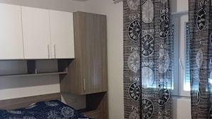 Une chambre à coucher avec un lit, une armoire et des rideaux ornés de motifs d’horloges.