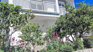 Un immeuble à plusieurs étages doté de balcons, entouré d’une végétation luxuriante et de plantes en fleurs.