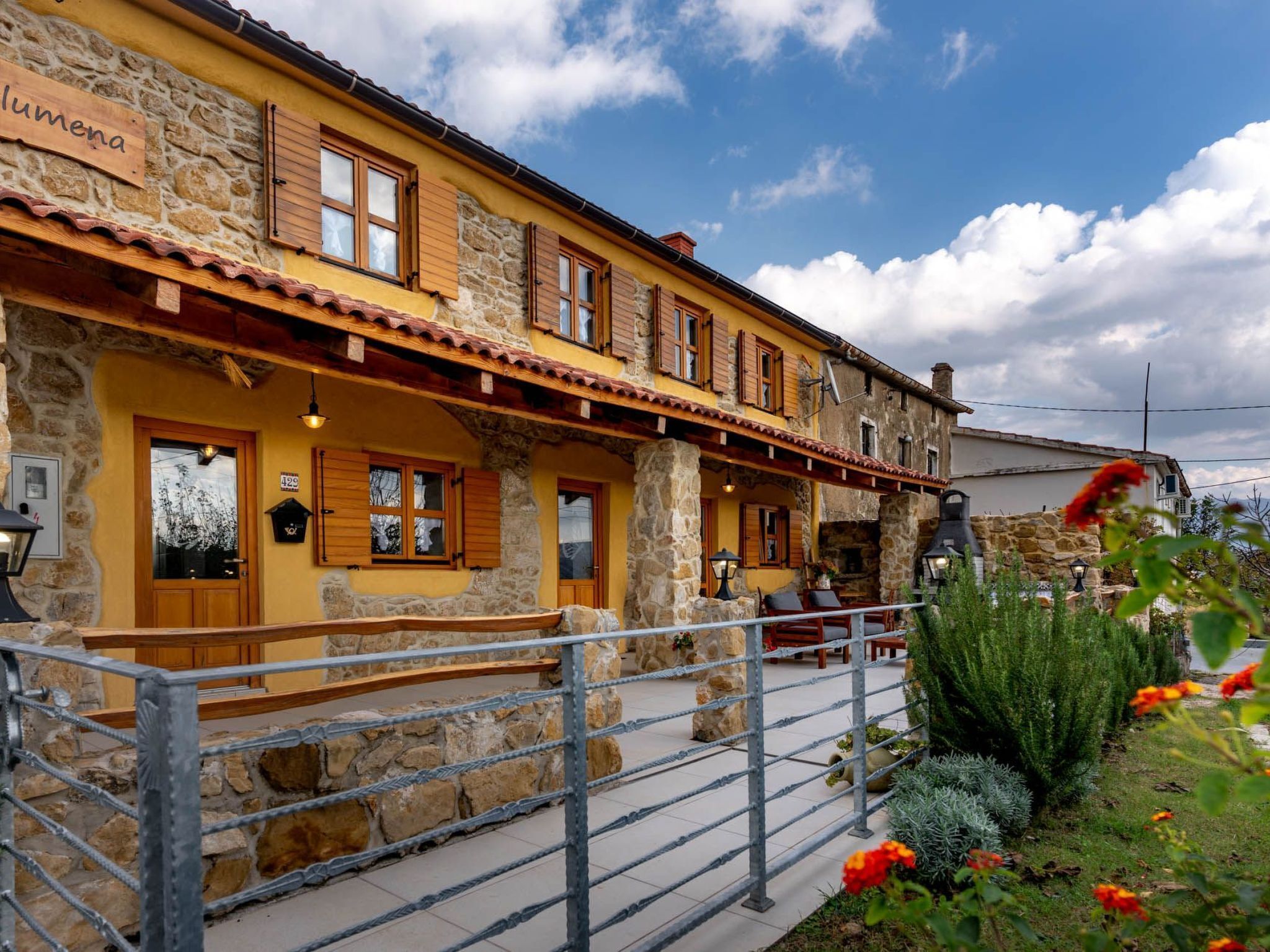 A traditional stone building with a yellow facade, wooden shutters, and a stone staircase leading to the entrance.