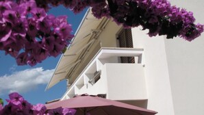 Ein weißes Gebäude mit Balkon und einer großen Sonnenschirm.