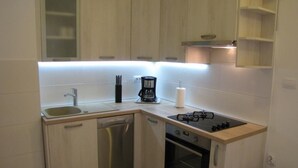 Eine kompakte Küche mit Geschirrspüler, Herd, Backofen und Kaffeemaschine.