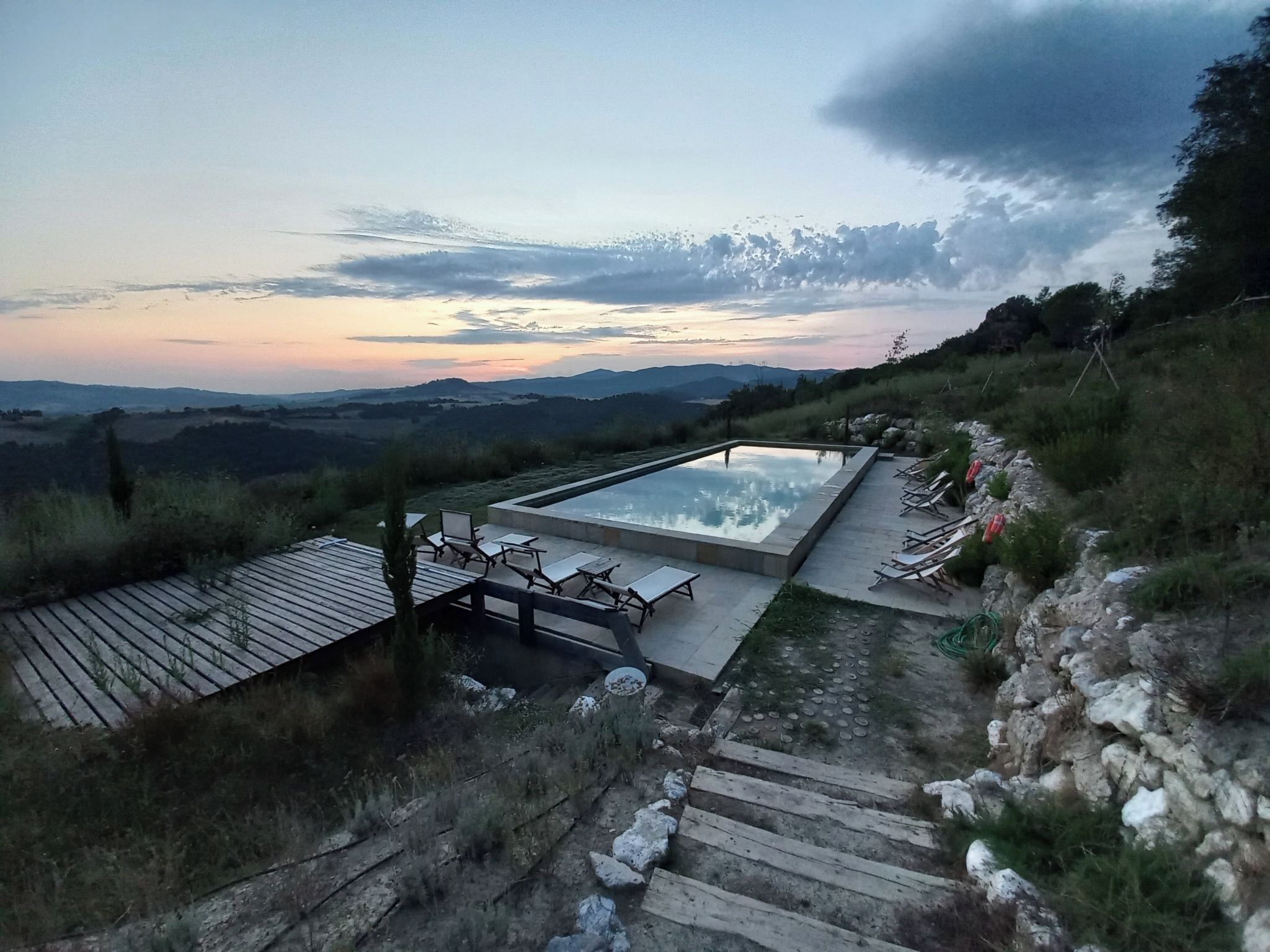 Una piscina con terraza, sillas de descanso y vistas del paisaje.