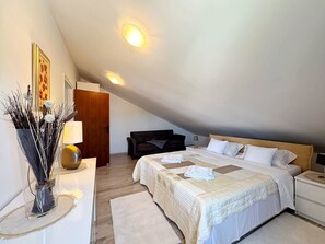 A bedroom with a large bed, two bedside tables, a nightstand, a wooden door, a wall-mounted lamp, and a decorative vase with branches. - Apartment Lure by Interhome (Polje)