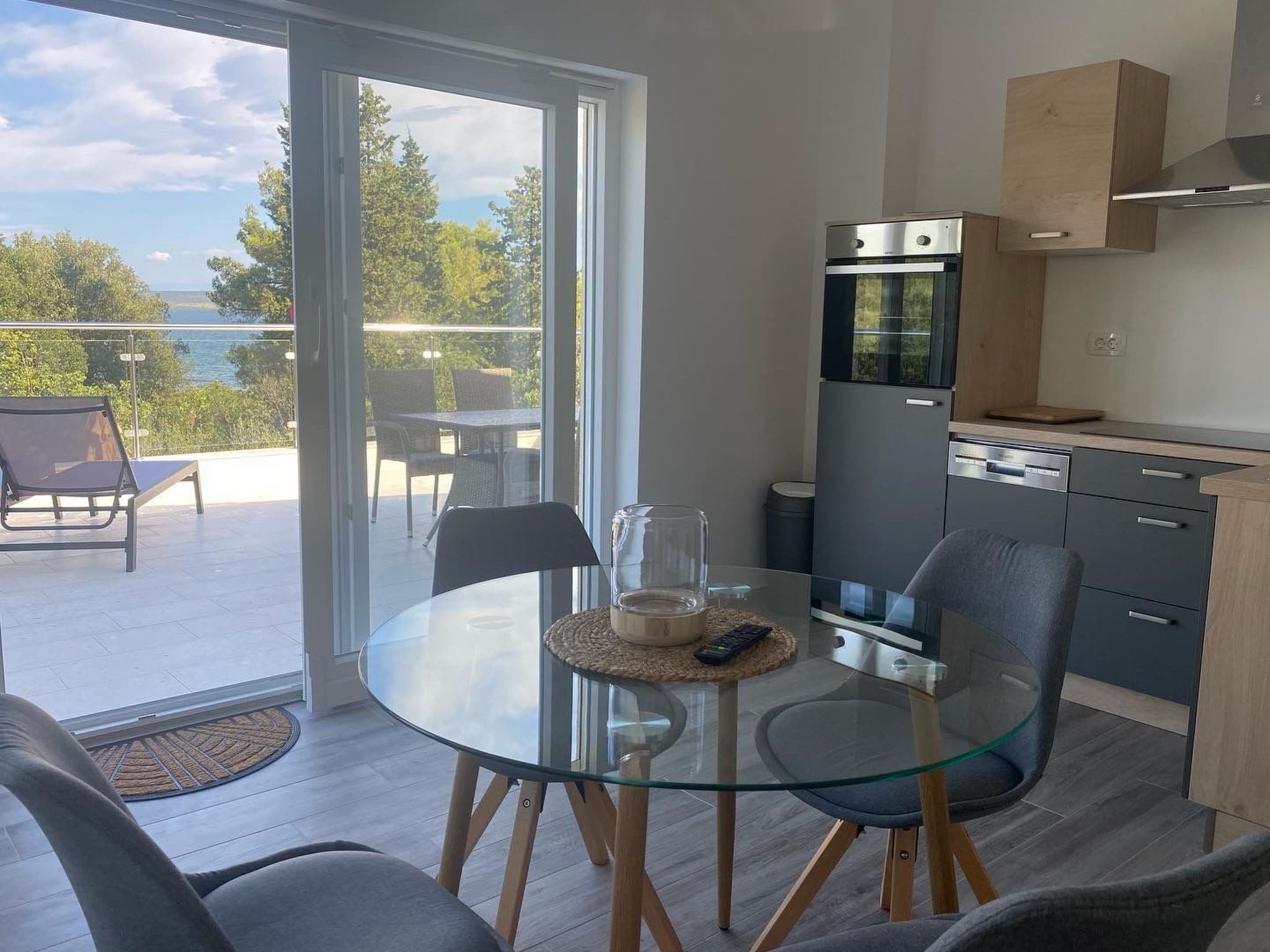A modern kitchen with a glass dining table, a built-in oven, and a view of the outdoors.