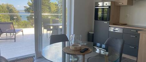 A modern kitchen with a glass dining table, a built-in oven, and a view of the outdoors.