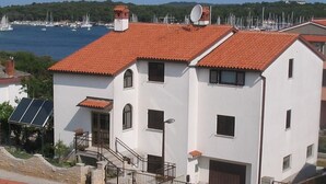 A white building with a red-tiled roof, a satellite dish, and a small satellite tower. - Wohnung 'Ida' Strandlage by Interhome (Pula)