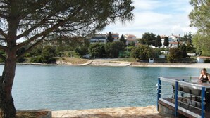 A lakeside view with a dock and a table with chairs. - Wohnung 'Ida' Strandlage by Interhome (Pula)