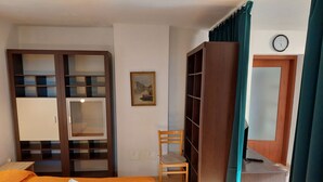 A hotel room with a bed, a desk, a chair, a wardrobe, and a painting on the wall. - Wohnung 'Ida' Strandlage by Interhome (Pula)