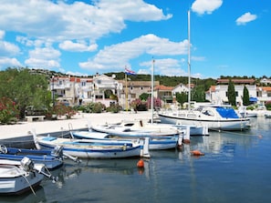 Uma marina com vários barcos atracados, cercada por edifícios com varandas e céu claro.