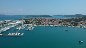 Eine Küstenstadt mit einem Yachthafen, voll mit Booten, umgeben von Wohngebäuden mit roten Dächern.