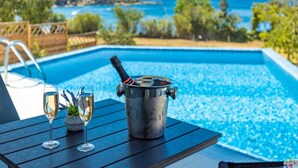 Ein Poolbereich mit Tisch, zwei Sektgläsern und einer Sektflasche.