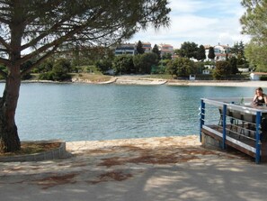 A lakeside view with a dock and a table with chairs. - Wohnung mit großer Terrasse by Interhome (Pula)