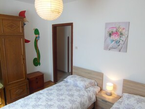 A bedroom with two beds, a wooden wardrobe, a small bedside table with a lamp, and a door leading to another room. - Wohnung mit großer Terrasse by Interhome (Pula)