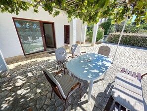 An outdoor patio with a table and chairs, a pergola with grapevines, and a stone-tiled floor. - Wohnung für 4-5 Personen mit Terrasse by Interhome (Crikvenica/Dramalj)