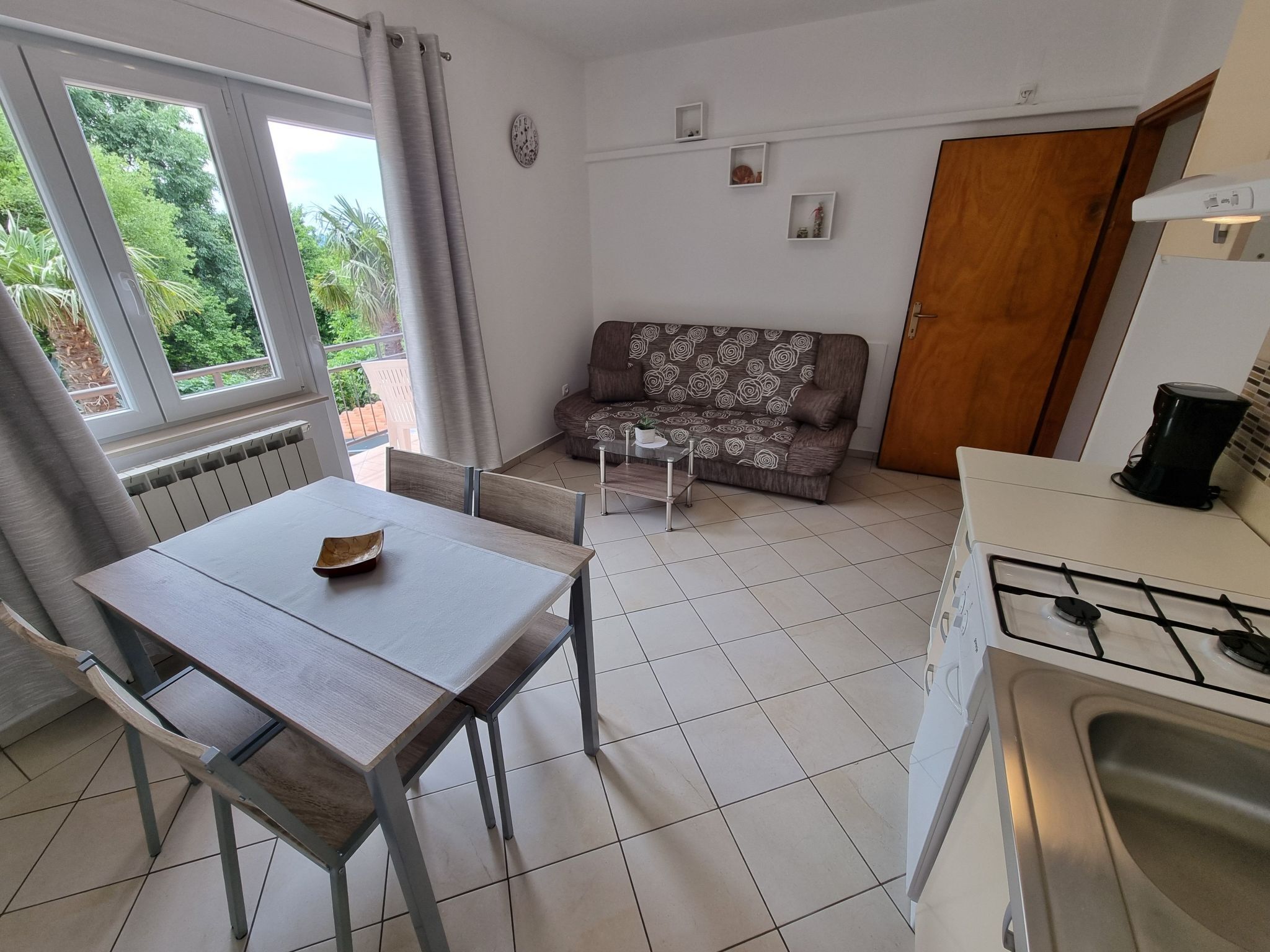 A compact kitchen with a dining table and chairs, a sofa, and a small coffee table.