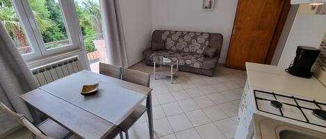A compact kitchen with a dining table and chairs, a sofa, and a small coffee table.