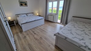 Un dormitorio con cama, mesita de noche, radiador y ventana con cortinas.
