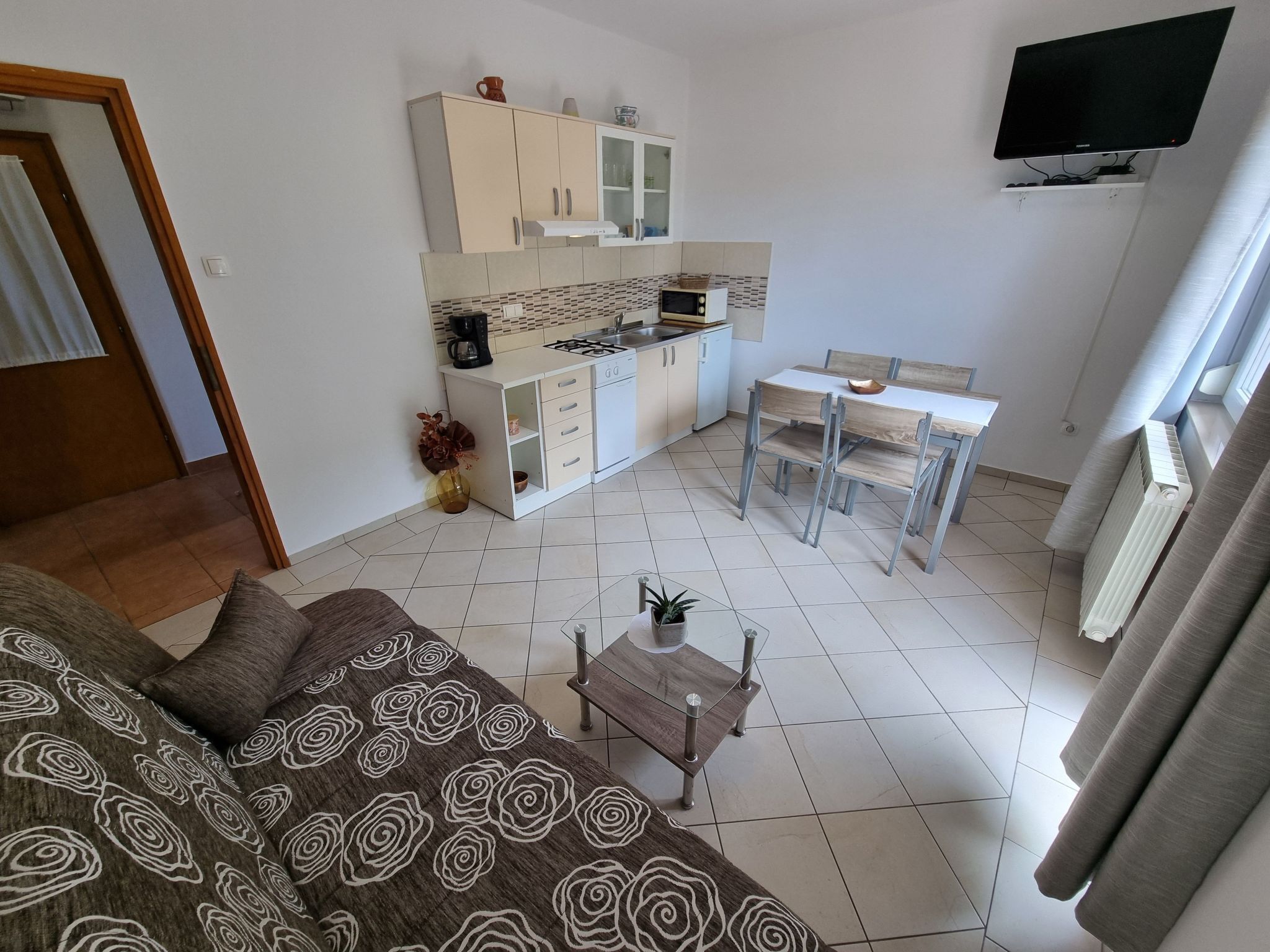 A compact living space with a kitchenette, a dining area, and a sofa.