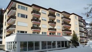 Ein mehrstöckiges Hotel mit Balkonen, einem überdachten Eingang und verschneitem Gelände.