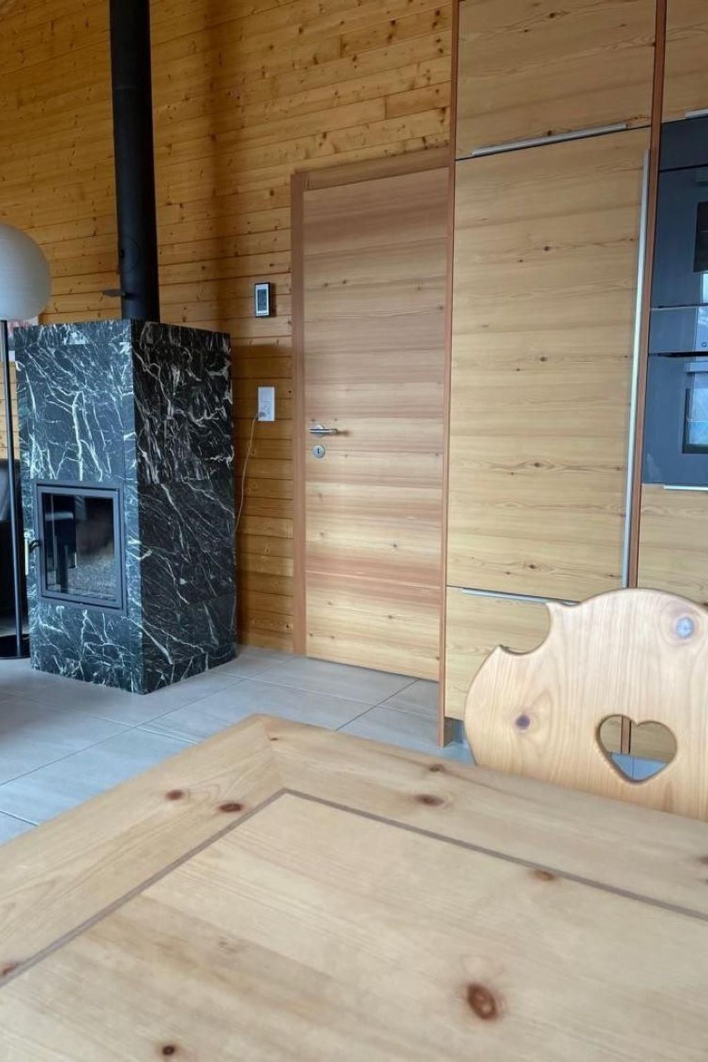 Ein Holzinterieur mit einem Marmor-Kamin, einer Holztür und einer herzförmigen Aussparung auf einem Tisch.
