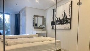 A bedroom with a bed, a vanity with a mirror, and a painting on the wall. - Ruhiges Ferienhaus mit großer offener Küche by Interhome (Anjum)