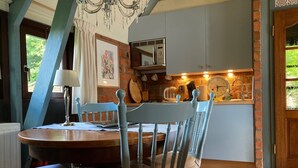 A dining area with a round table, chairs, a chandelier, and a kitchen in the background. - haus am Deich! by Interhome (Anjum)