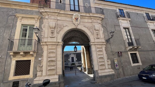 Un arco de piedra ornamentado con tallas intrincadas y un balcón en el nivel superior.