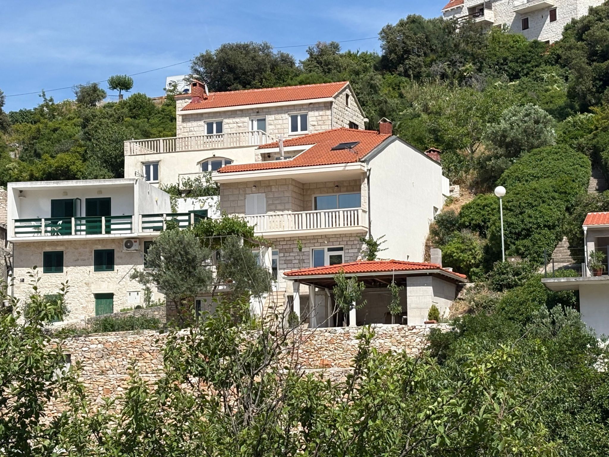 A multi-story building with a stone facade, red-tiled roofs, and balconies.