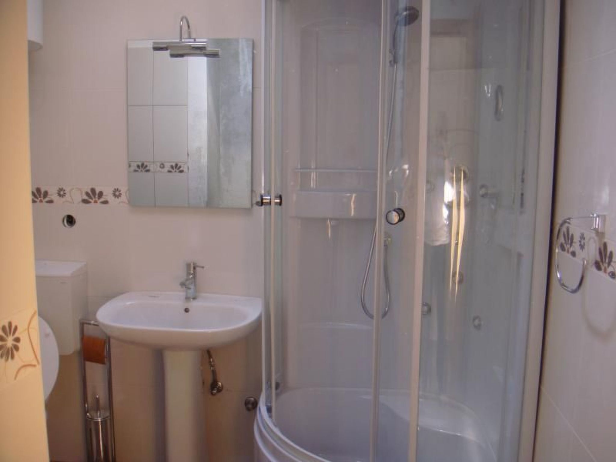 A bathroom with a glass-enclosed shower, a sink, and a toilet.