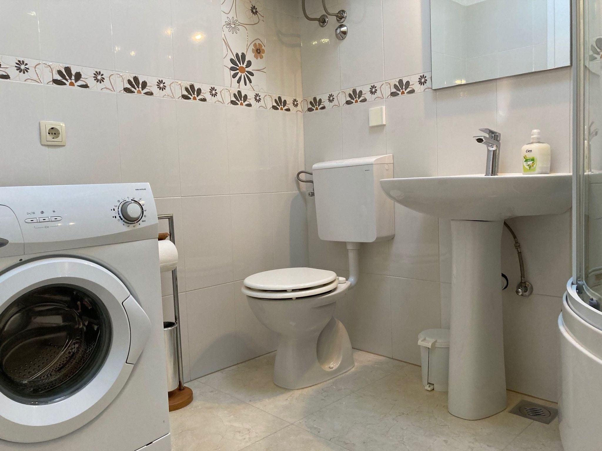 Een kleine badkamer met een wasmachine, toilet, wastafel en een spiegel.
