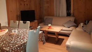 A cozy cabin interior with a dining area, sofa, and television.
