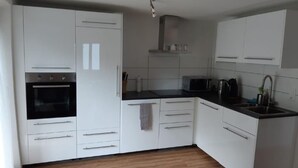 A modern kitchen with white cabinets, a black oven, a microwave, and a sink.