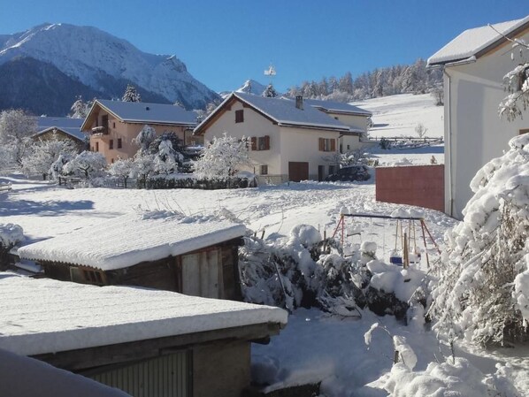 A snowy residential area with houses, a mountain in the background, and a clear sky.