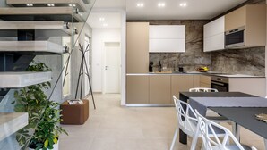A modern kitchen with a marble backsplash, a dining area with a table and chairs, and a staircase with a glass railing. - "Villa Tango2" mit Blick auf das Wasser by Interhome (Trogir/Okrug Donji)