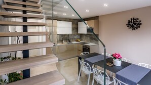 A modern kitchen with a glass staircase, white cabinets, and a dining area with a table and chairs. - "Villa Tango2" mit Blick auf das Wasser by Interhome (Trogir/Okrug Donji)