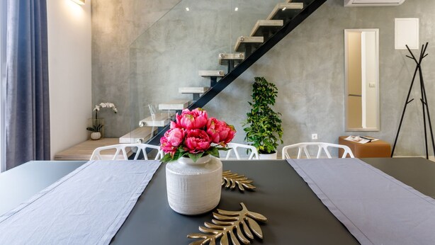 A modern dining area with a table set for two, a vase of flowers, and a staircase in the background. - "Villa Tango2" mit Blick auf das Wasser by Interhome (Trogir/Okrug Donji)