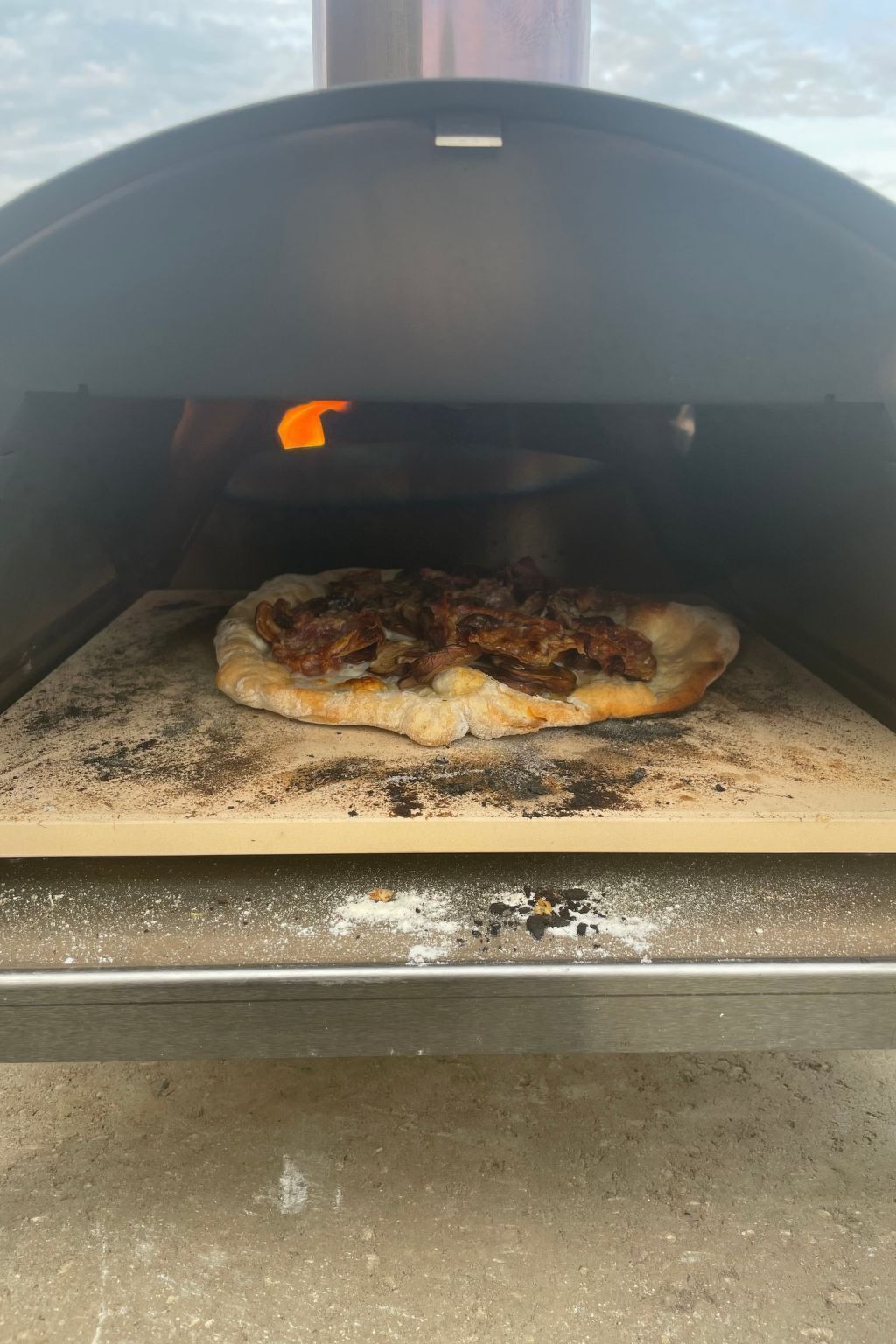 A pizza inside a wood-fired oven.