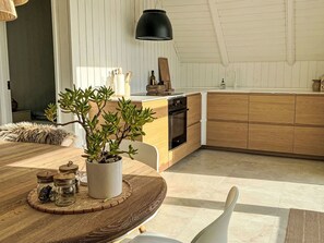 Eine moderne Küche mit Holzausstattung, einer zentralen Kochinsel und einem Blumentopf.