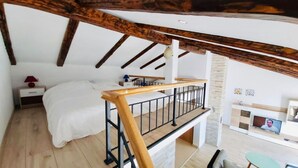 A bedroom with a bed, a nightstand, a desk, and a staircase leading to an upper level. - Apartment Karlo auf zwei Wohnebenen, mit Meerblick by Interhome (Rab/Supetarska Draga)