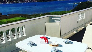 A white table with four cups and saucers, a red teapot, and a white bowl on a balcony overlooking a body of water. - Apartment Karlo auf zwei Wohnebenen, mit Meerblick by Interhome (Rab/Supetarska Draga)
